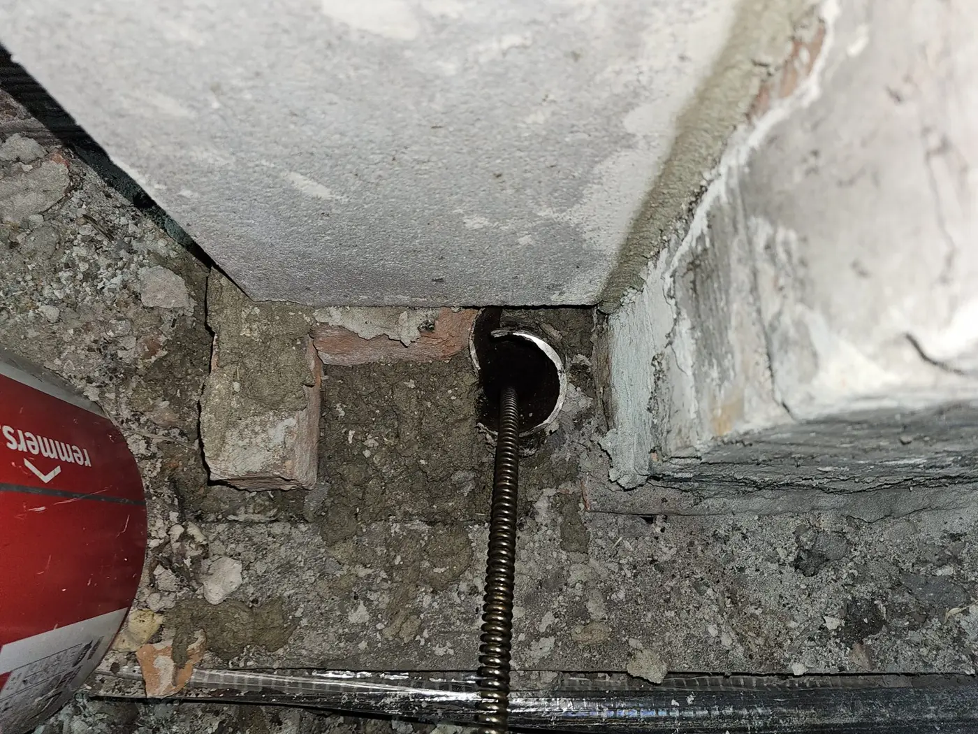 Spirala elektrycznej sprężyny 16 mm wprowadzona pionowo do kielicha żeliwnego pionu w podłodze poddasza