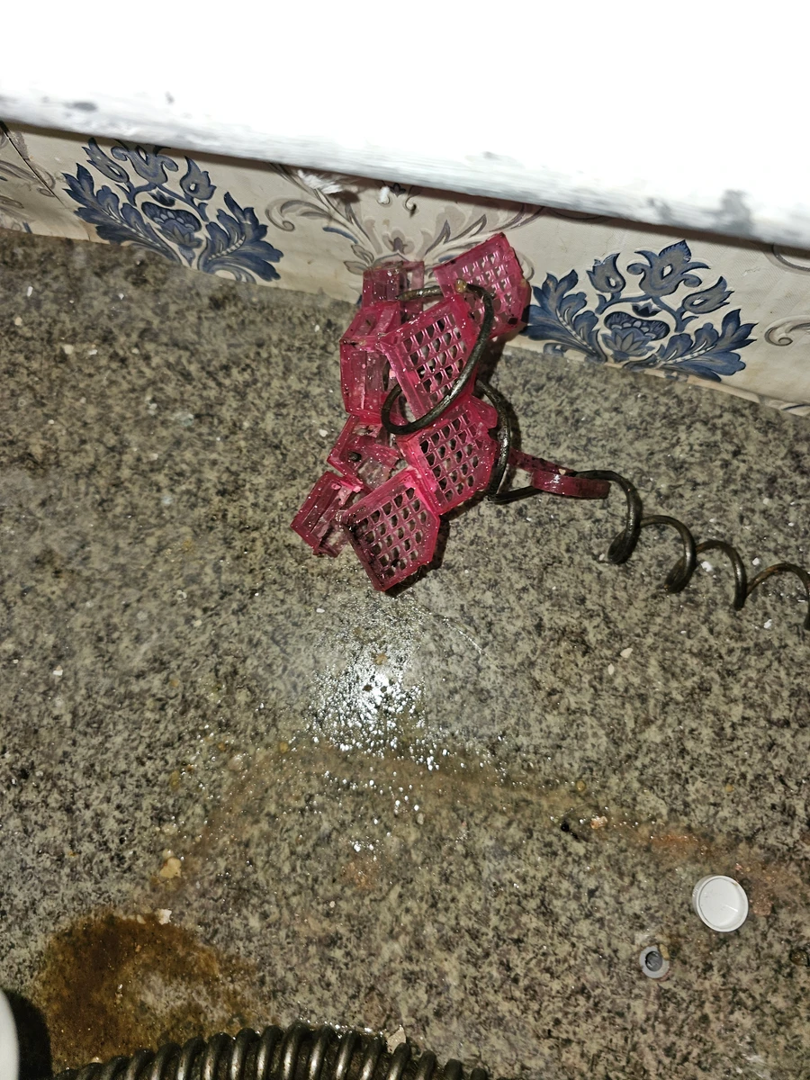 Różowa zawieszka toaletowa wyciągnięta z pionu kanalizacyjnego na chwytaku spirali